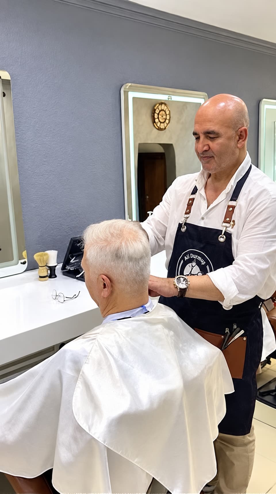 Ali Bey, beyaz saçlı bir müşterinin ense çizgisini düzeltiyor